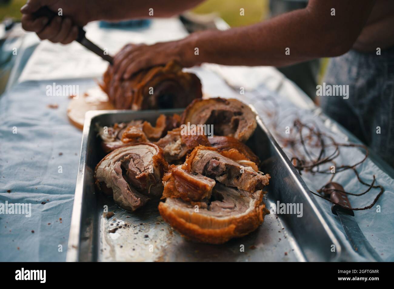 Zugeschnittenes Foto von Menschenhänden, die Schweinefleisch schneiden Stockfoto