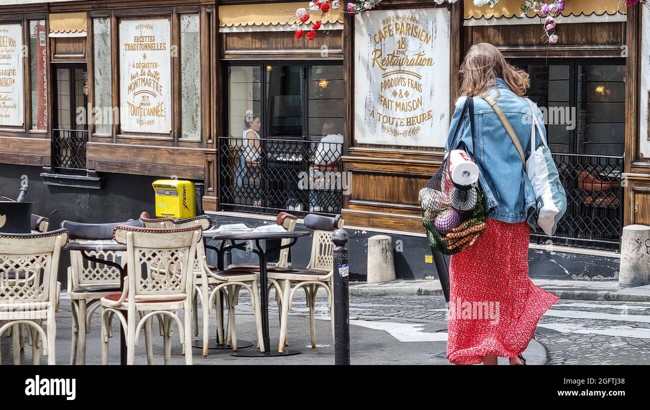 Paris, Frankreich - Juli 2021: Junge Frau, die Lebensmittel aus Plastik und Gemüse in einer wiederverwendbaren Tasche auf der Straße in Paris trägt.Monmartre Street. Stockfoto