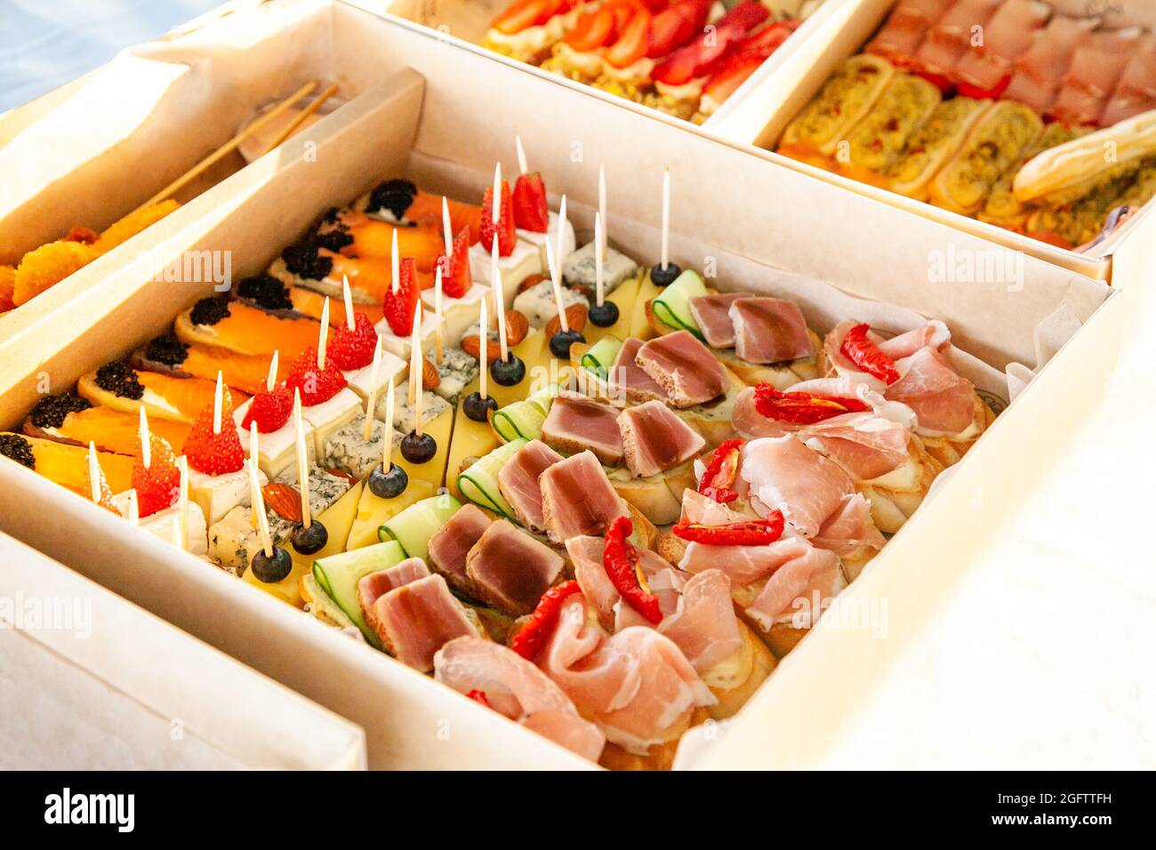 Gourmet-Snacks in Pappkarton mit Sandwiches, Eklairs, Bruschetta mit Aufschnitt, Käse und Meeresfrüchten für Catering-Buffet und Party. Stockfoto