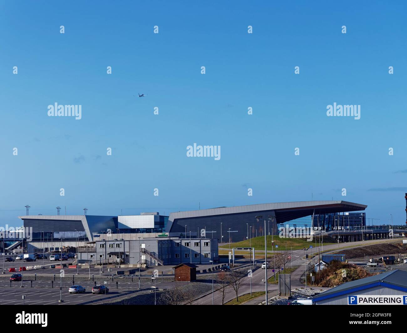 Ein ruhiger Flughafen Bergen Flesland mit einem Flugzeug, das in der Ferne über dem modernen Terminalgebäude abfliegt und leeren Parkplätzen während des Covid Stockfoto