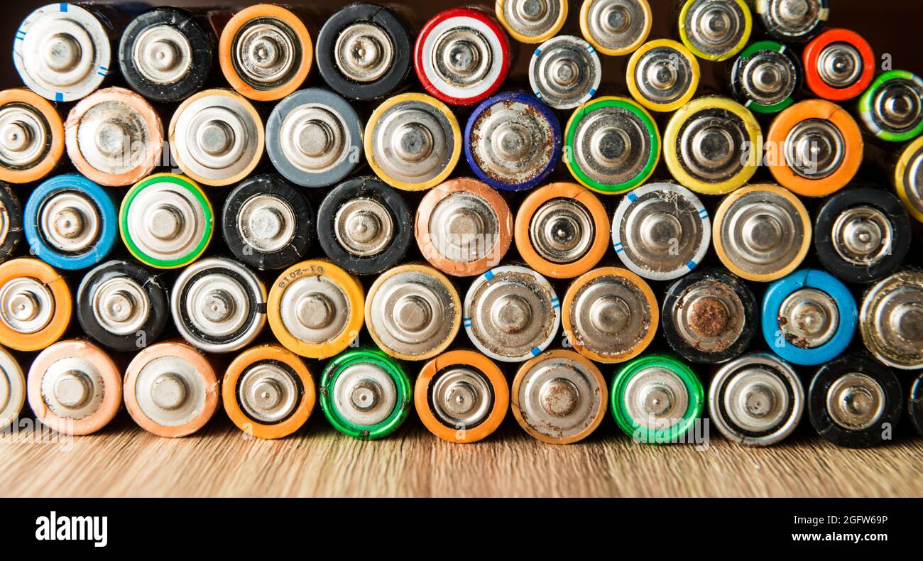 Flache Batterien ordentlich auf einem Holztisch platziert. Konzept des Recyclings und der Pflege der Umwelt. Stockfoto