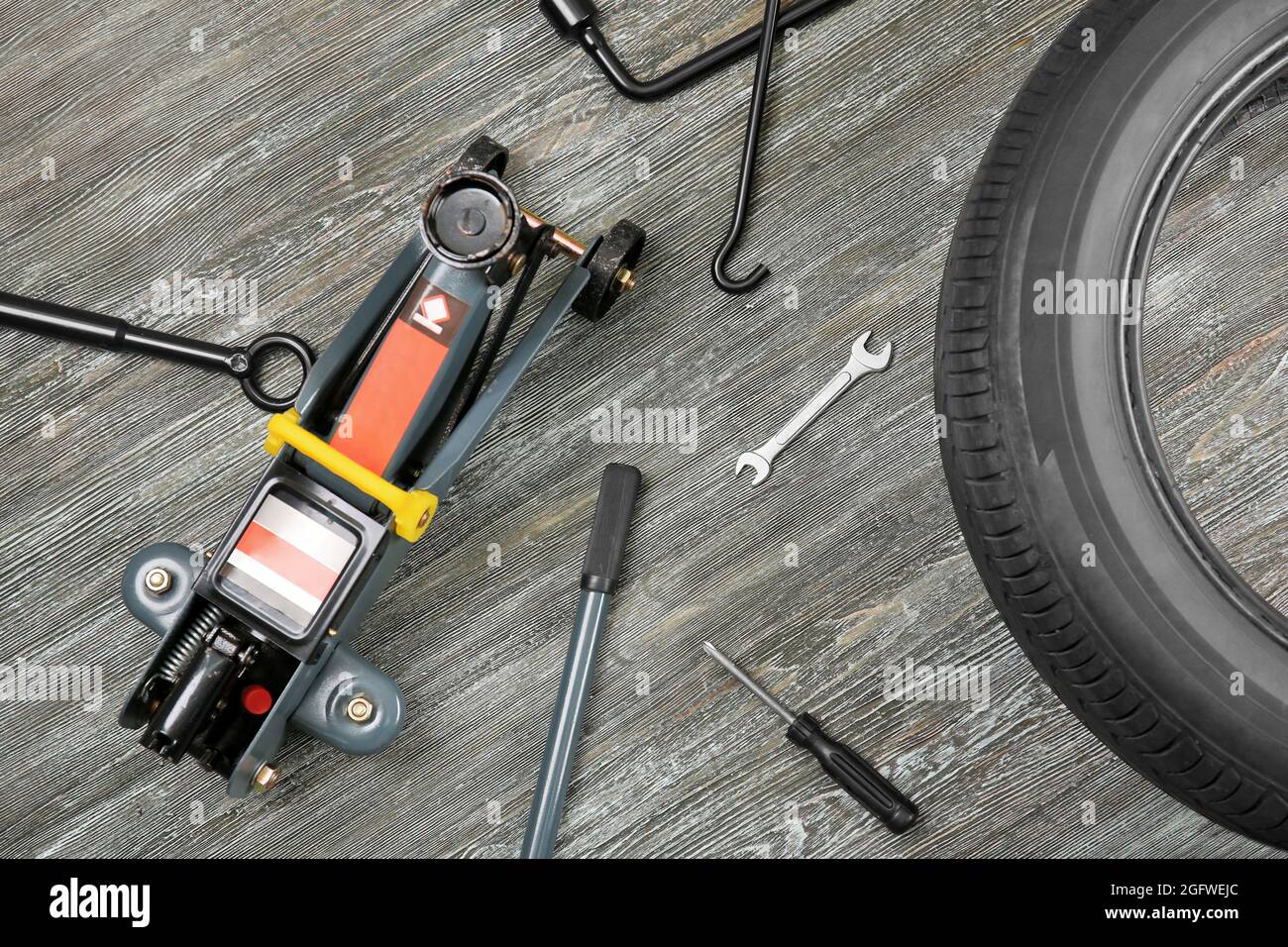 Wagenheber mit Werkzeugen und Reifen auf Holz- Hintergrund Stockfotografie  - Alamy