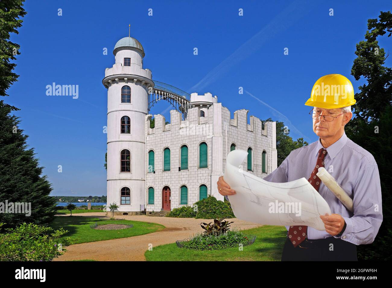 Architekt mit Bauplan und Hut vor einer im Bau befindlichen Burg Stockfoto