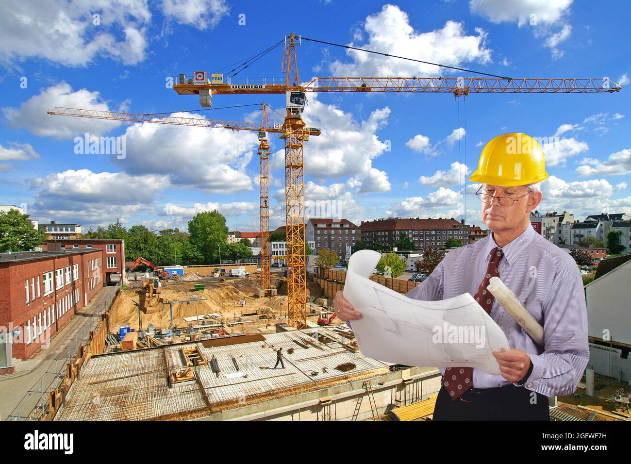 Architekt mit Bauplan und Hut, Baustelle im Hintergrund Stockfoto