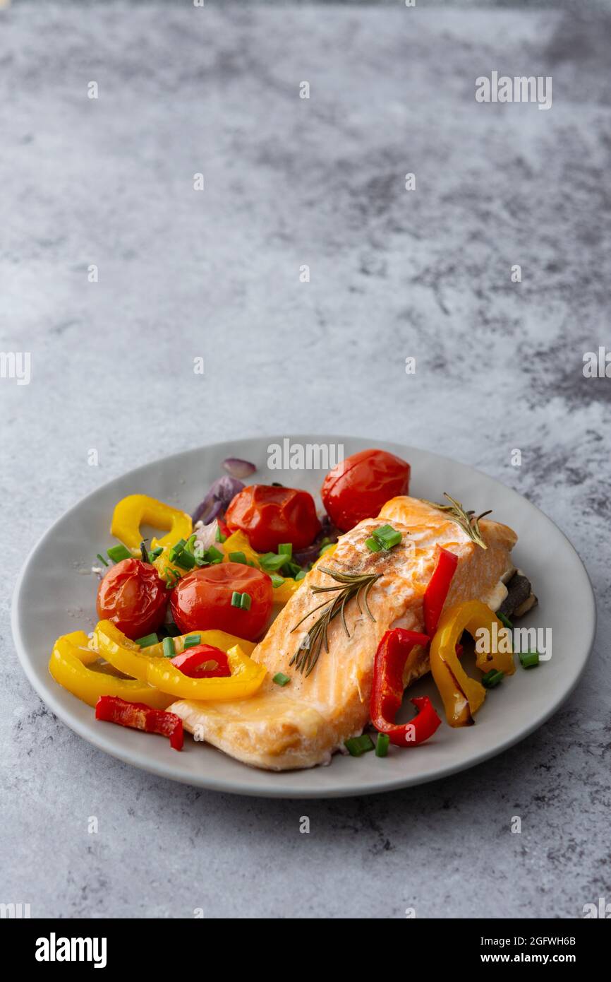 Gebackenes rotes Fischfilet Arktischer Saibling auf einem Teller mit Gemüse aus nächster Nähe, leckeres herzhaftes, gesundes Abendessen Stockfoto