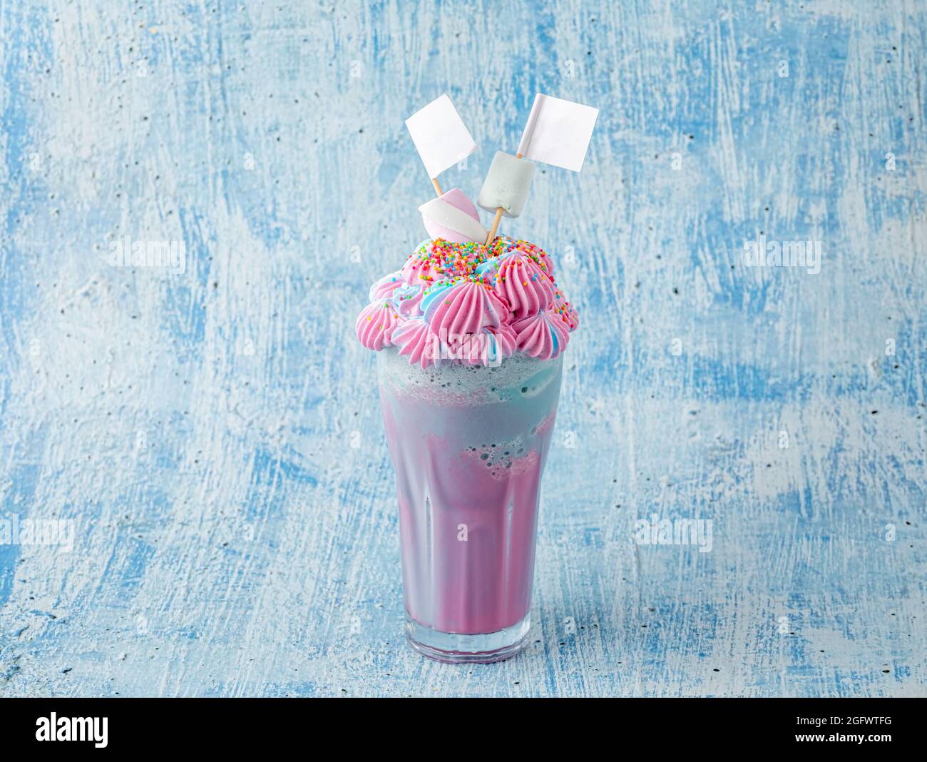 Blauer und rosafarbener Milchshake mit Marshallows auf blauem Hintergrund. Stockfoto