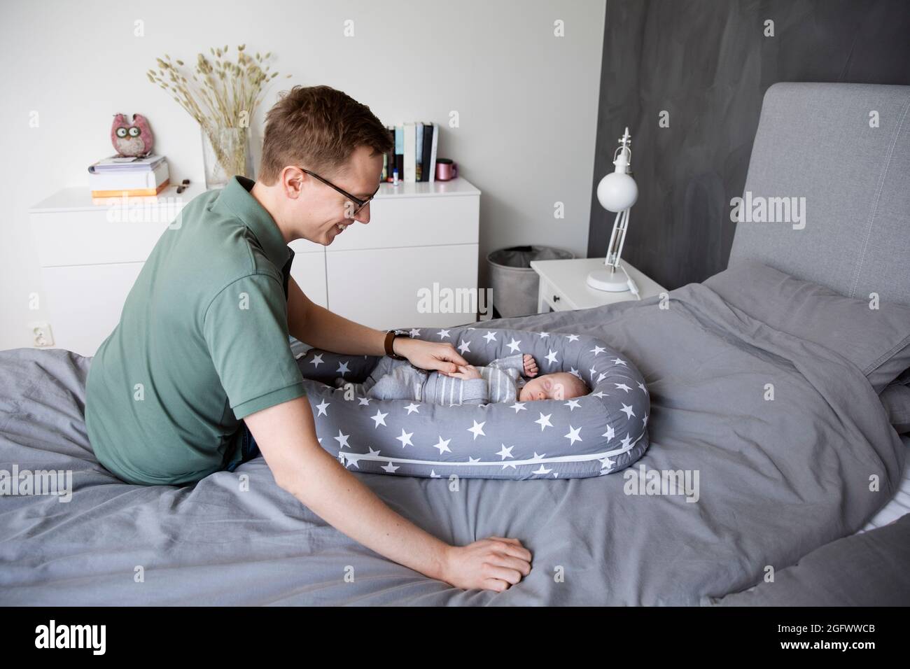 Vater legt Baby Sohn schlafen Stockfoto