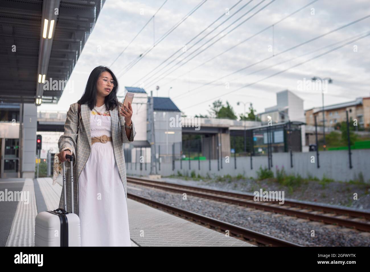 Frau telefoniert am Bahnhofsplatz Stockfoto