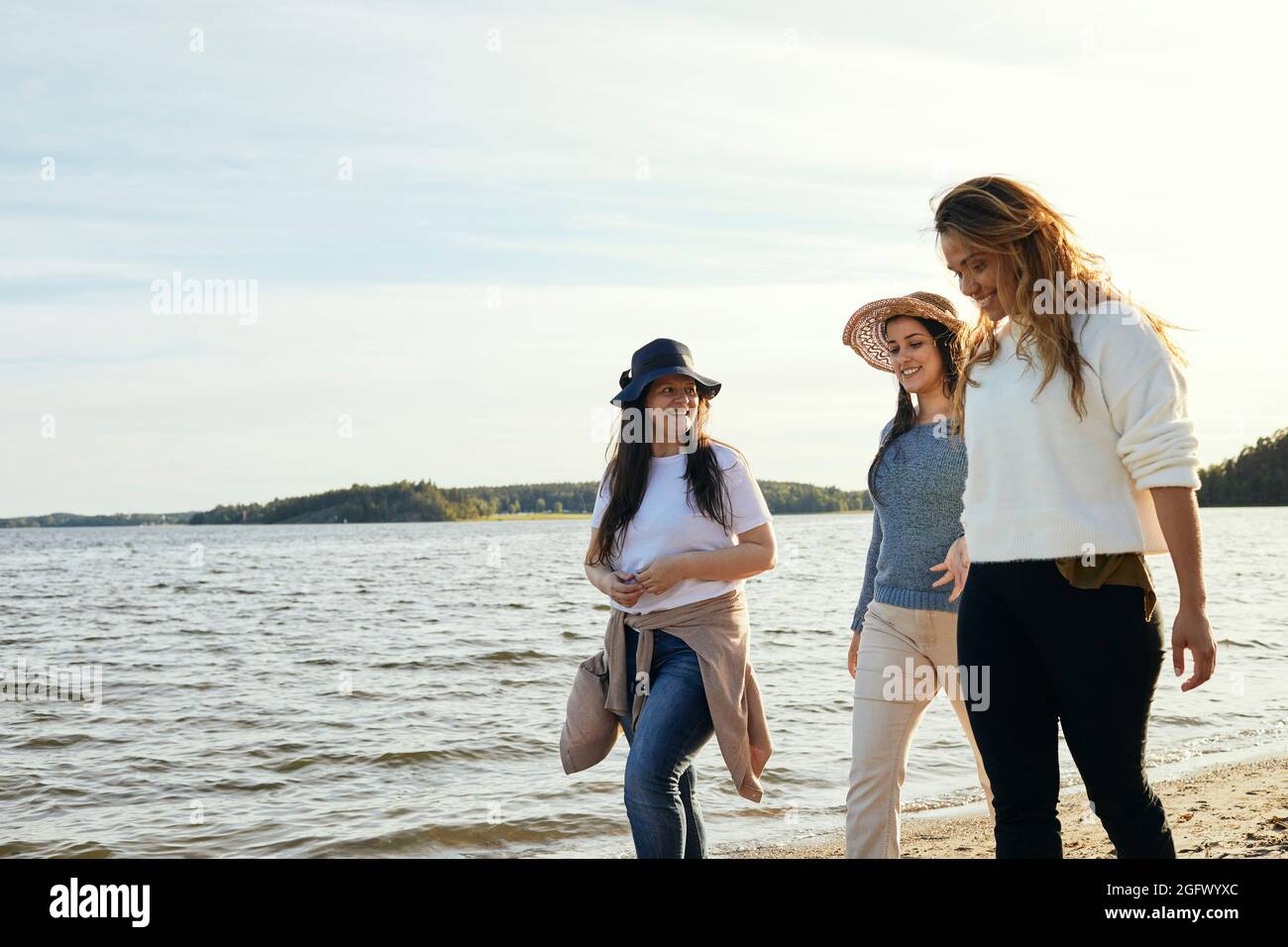 Freundinnen, die auf dem Meer spazieren Stockfoto