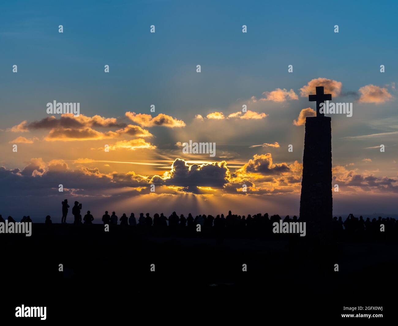 Silhouetten von Menschen und ein großes Kreuz vor der Kulisse eines fabelhaften Sonnenuntergangs am Ende Europas, Cabo Da Roca, Portugal Stockfoto