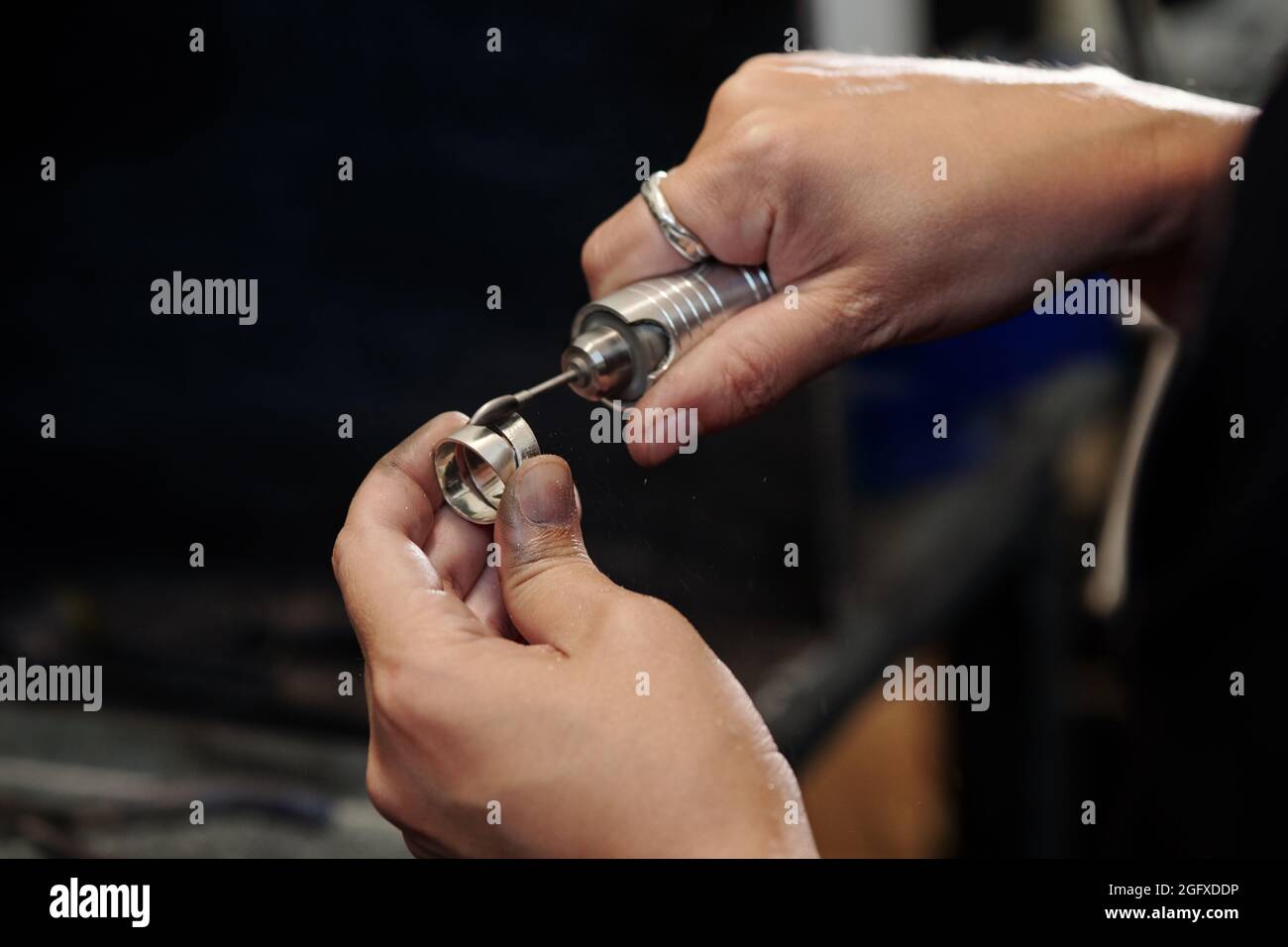 Nahaufnahme eines nicht erkennbaren Juweliers aus der Fertigung mit Polierkegel, der auf einem flexiblen Schaft montiert ist, während der Silberring gereinigt wird Stockfoto