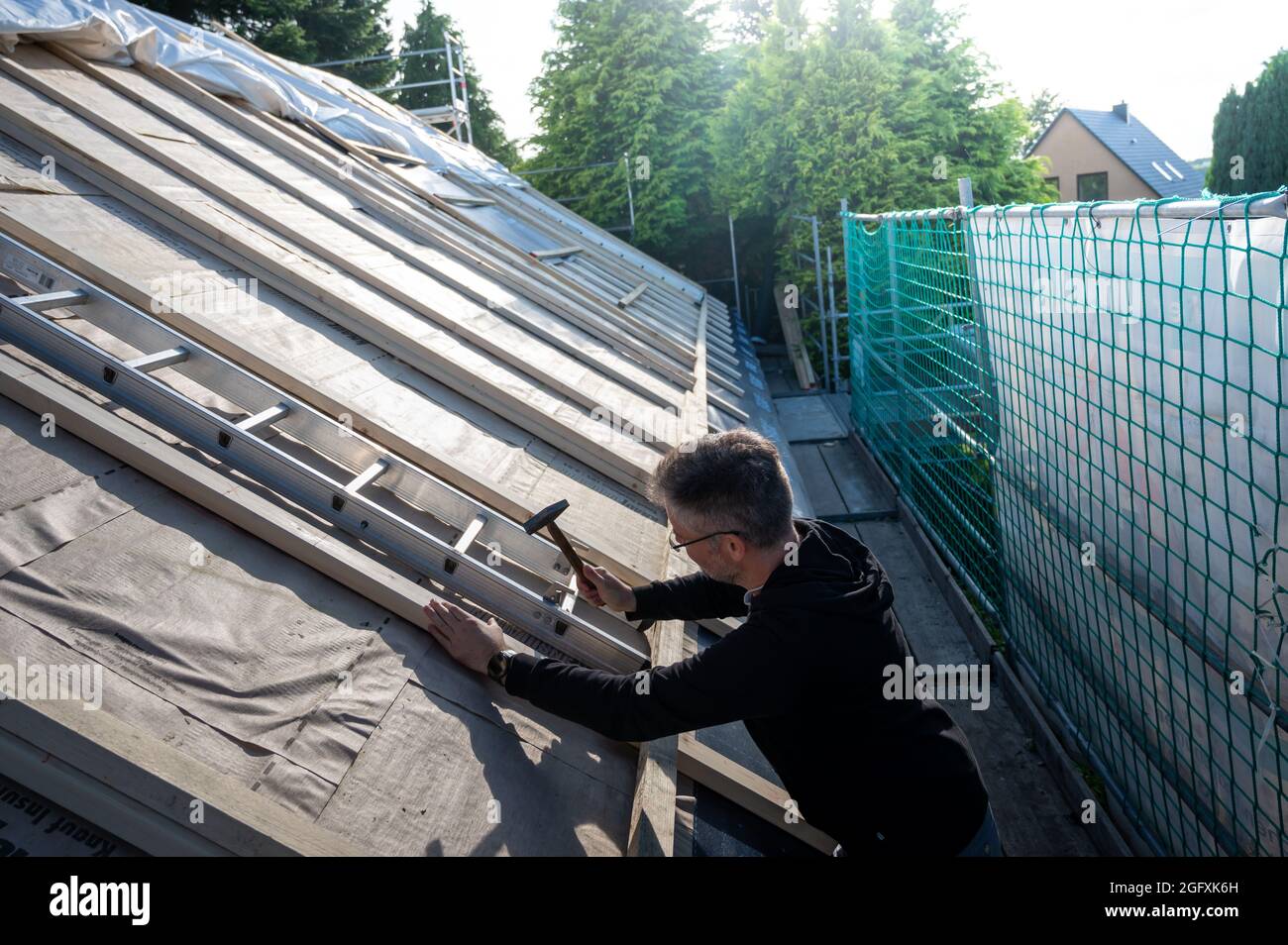 Dachdecker zur Befestigung einer neuen Isolierung auf dem Dach eines alten Hauses. Stockfoto