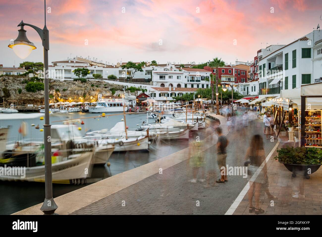 Menorca, Spanien - 20. august 2021: Menschen im Hafen es Castell, bei Sonnenuntergang touristische Stadt mit weißer Architektur und Gebäuden in Menorca, Spanien Dur Stockfoto