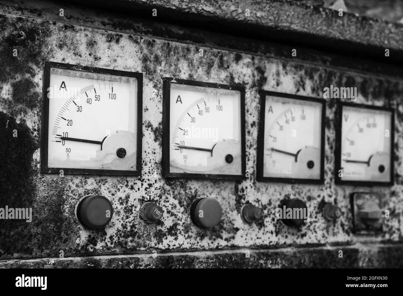 Industrielle quadratische Amperemeter in einer Reihe, montiert in einem grungigen alten Bedienfeld, Nahaufnahme von Schwarzweiß-Fotos mit selektivem Weichfokus Stockfoto