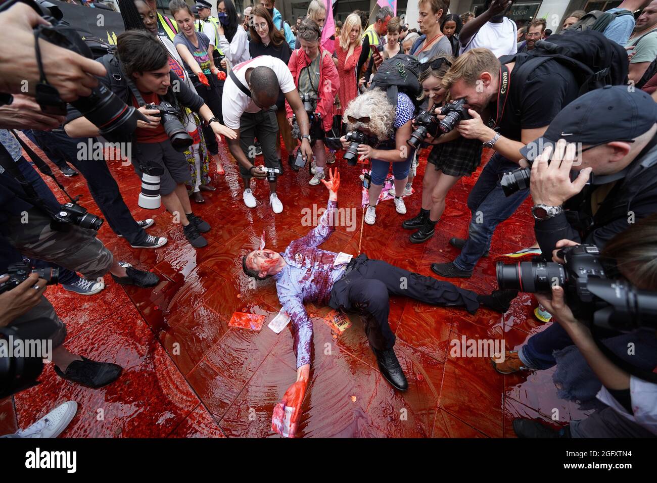 Ein Mitglied der Extinction Rebellion rollt in gefälschtem Blut auf dem Peternoster Square im Zentrum von London herum. Bilddatum: Freitag, 27. August 2021. Stockfoto