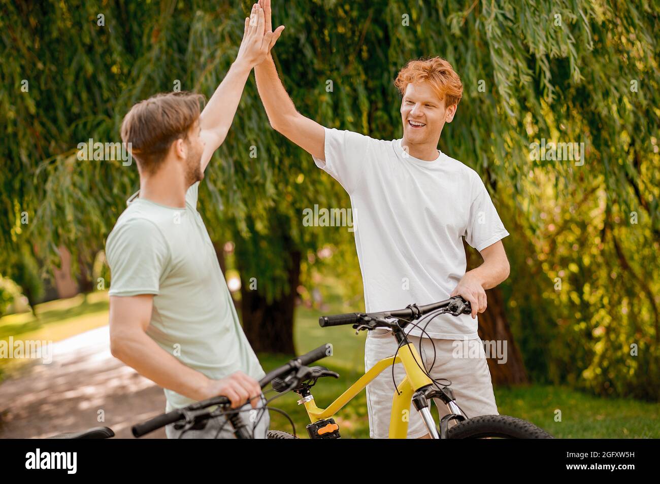 Ein fröhlicher, sportlicher junger Mann begrüßt seinen kumpel in einem Park Stockfoto