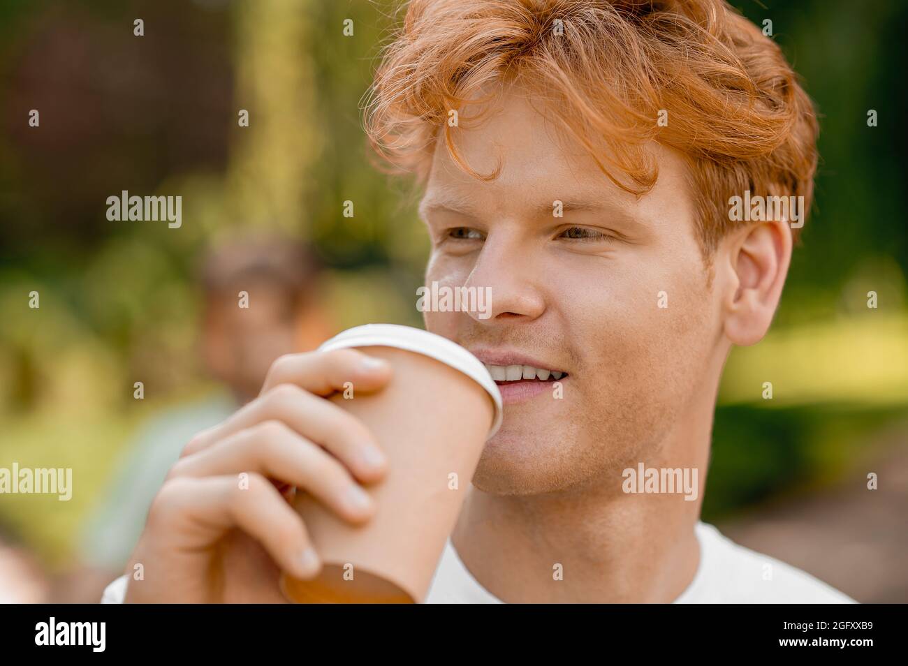 Schöner, zufriedener junger Mann, der eine Kaffeepause im Freien hat Stockfoto