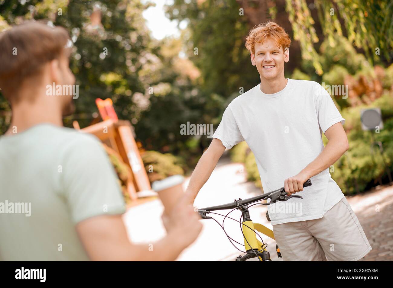 Zufriedener junger Radfahrer, der sich mit seinem kumpel unterhielt Stockfoto