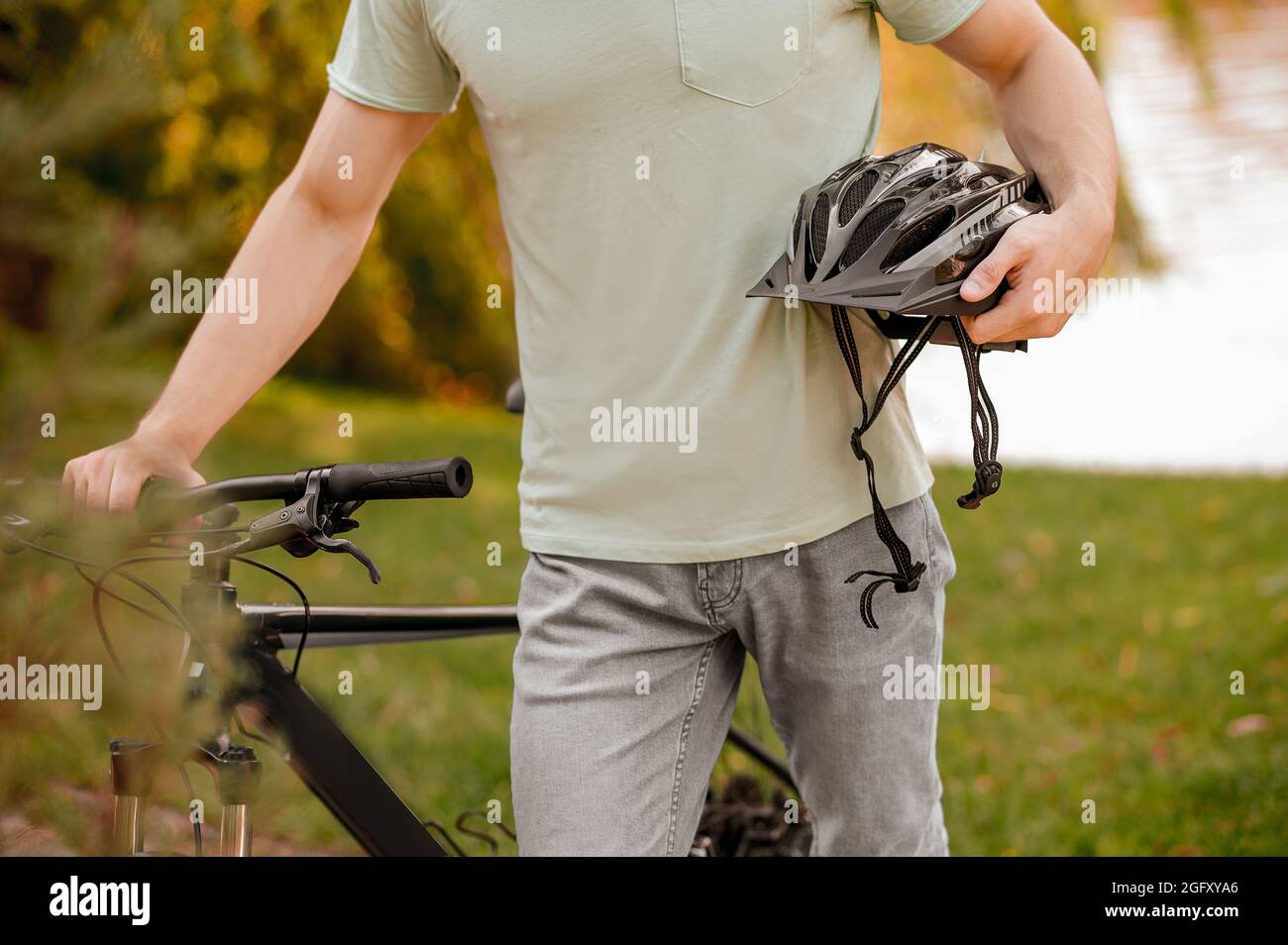 Männlicher Athlet mit seinem Fahrrad und seiner schützenden Kopfbedeckung, die draußen steht Stockfoto