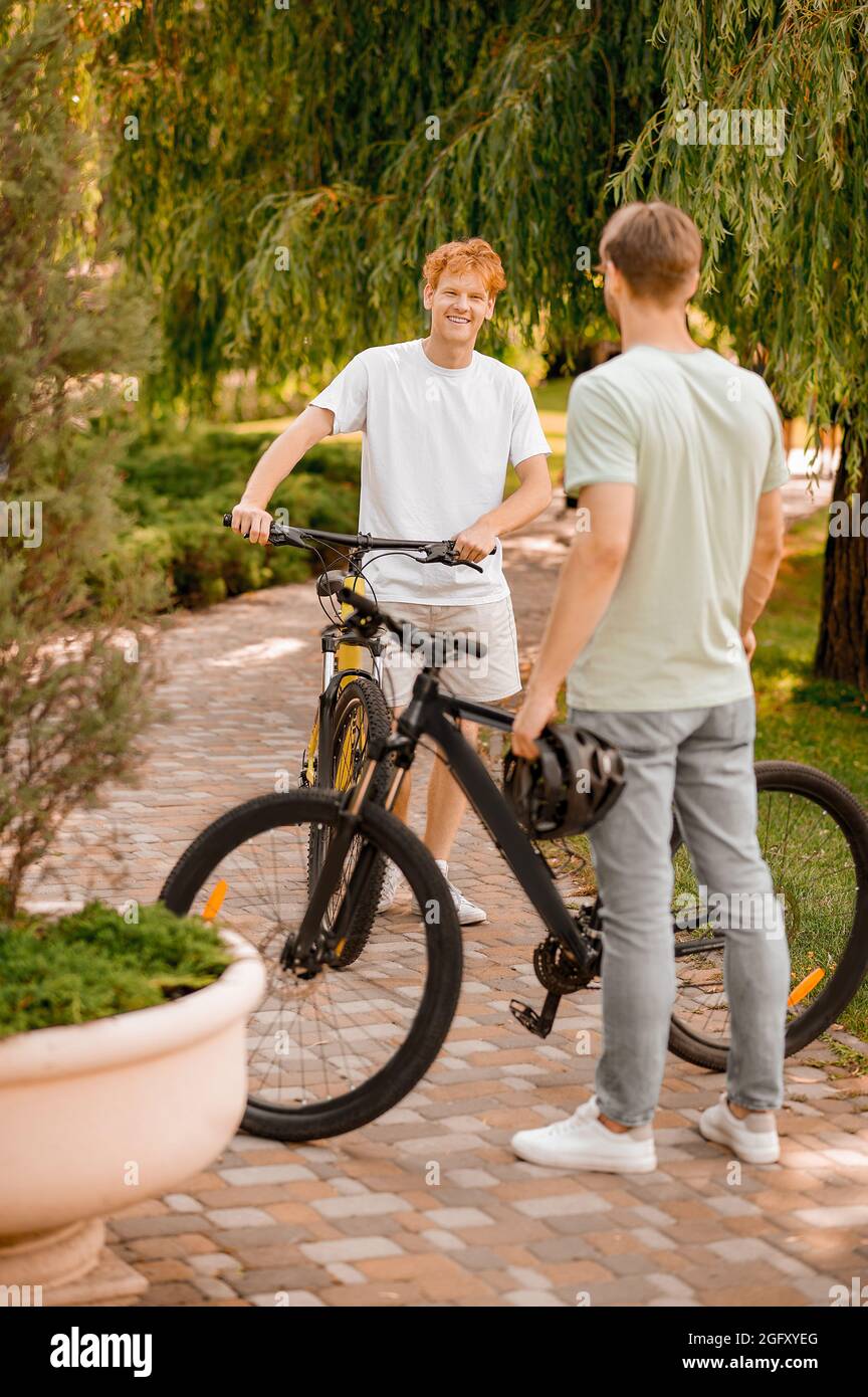 Zufriedener Fahrradfahrer, der mit seinem freund im Freien spricht Stockfoto