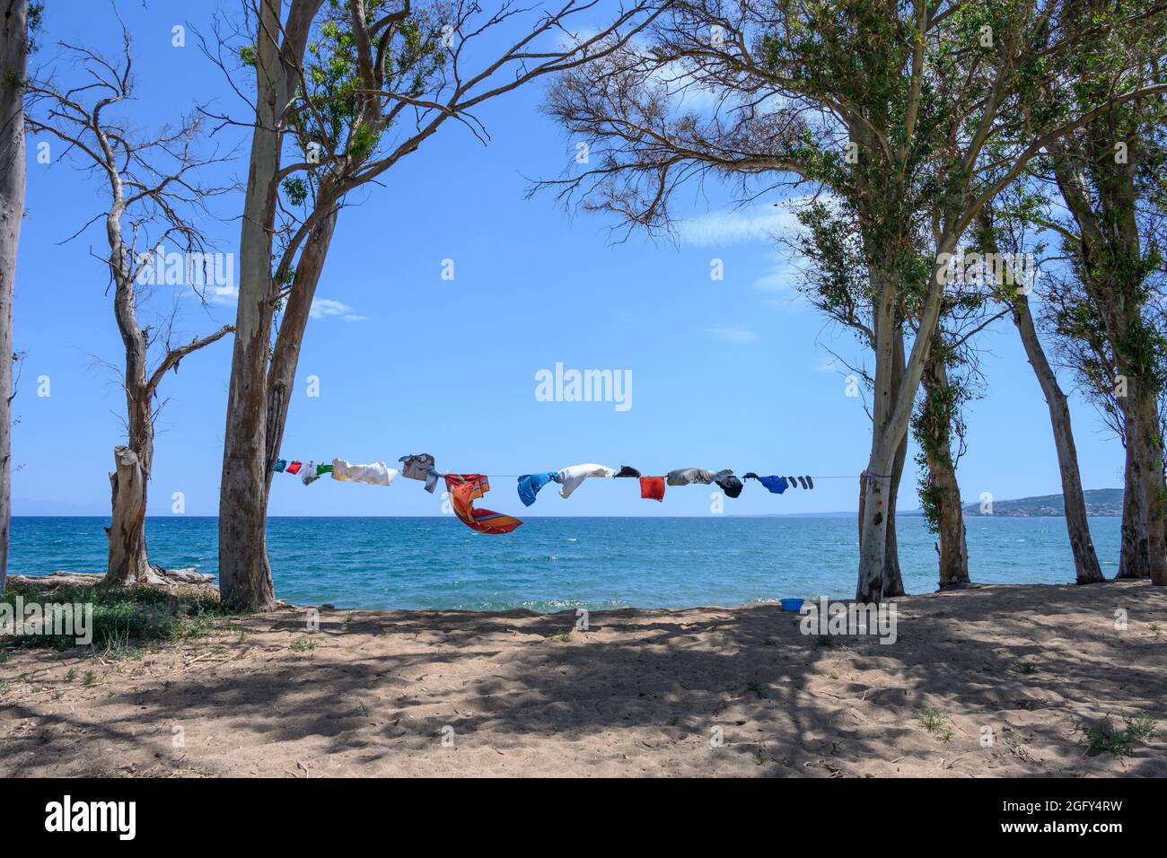 Camper Kleidung trocknen auf einer Wäscheleine, aufgereiht zwischen Bäumen, neben dem Meer an einem Strand in Südgriechenland. Stockfoto