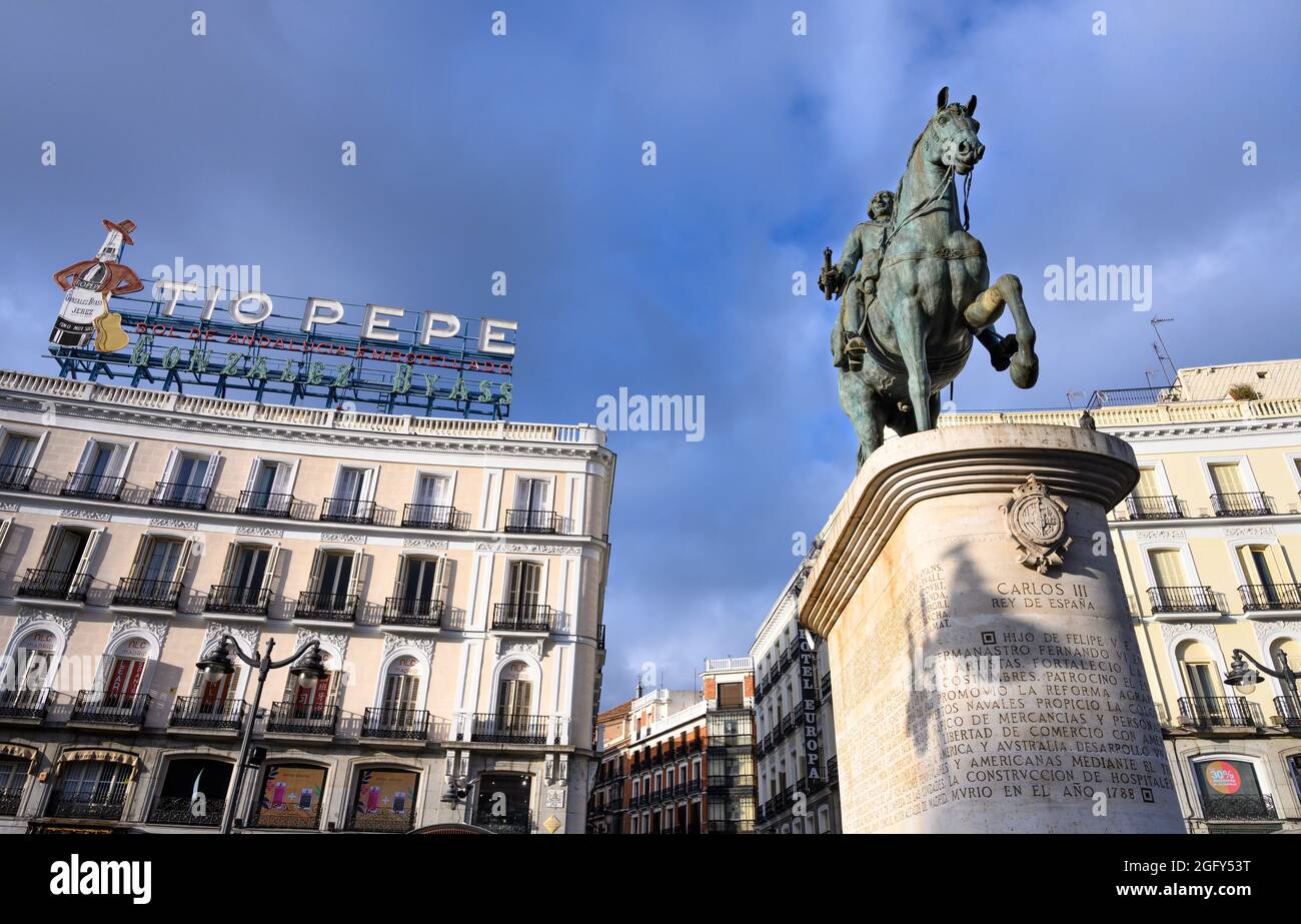 Das berühmte Tio Pepe Reklameschild erhebt sich über eine Statue von König Carlos III, an der Puerta del Sol, Madrid, Spanien. Stockfoto