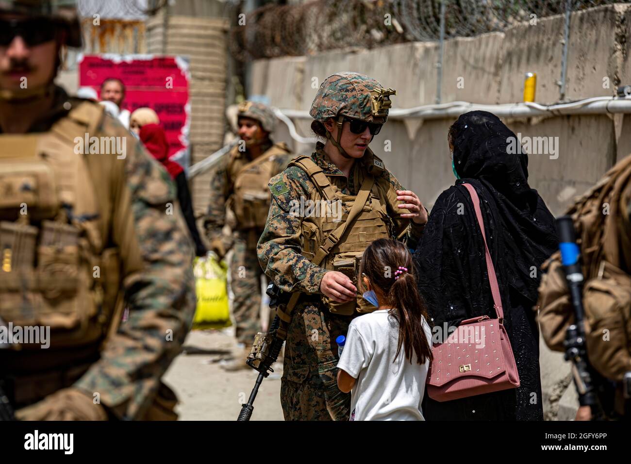 Eine Marine unterstützt eine Frau und ein Kind während einer Evakuierung am Hamid Karzai International Airport, August 18. US-Dienstmitglieder unterstützen das Außenministerium bei einer geordneten Abseichung von designiertem Personal in Afghanistan. (USA Marine Corps Foto von 1st Seal. Mark Andries) Stockfoto