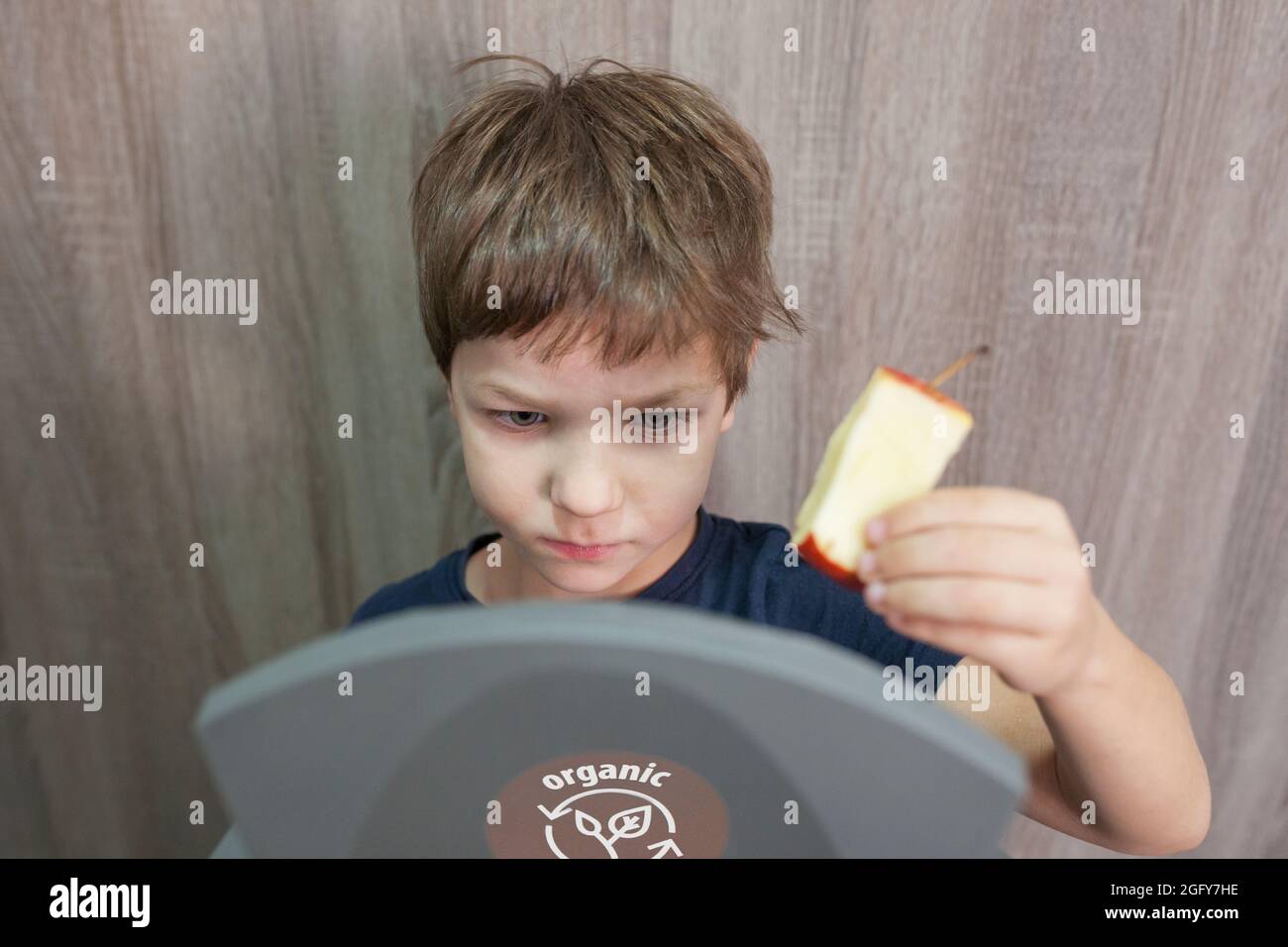 Kind Junge werfen Apfelkern zu Abfalleimer für Bio zu Hause. Aufklärung über das Konzept der Abfalltrennung Stockfoto