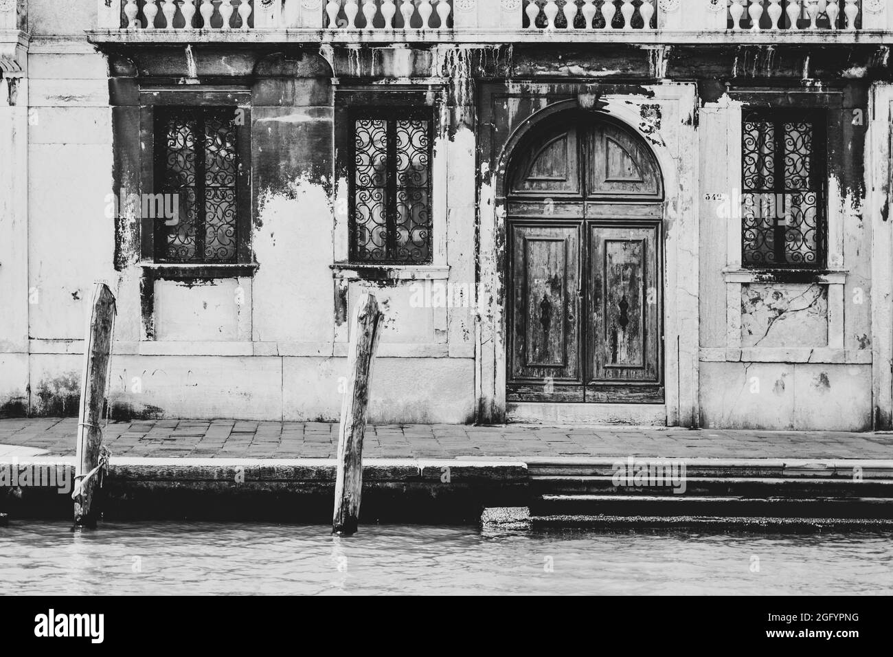 Romantische venezianische Ecke mit Vintage-Holztür und Fenstern. Venedig, Italien. Schwarzweiß-Bild. Stockfoto