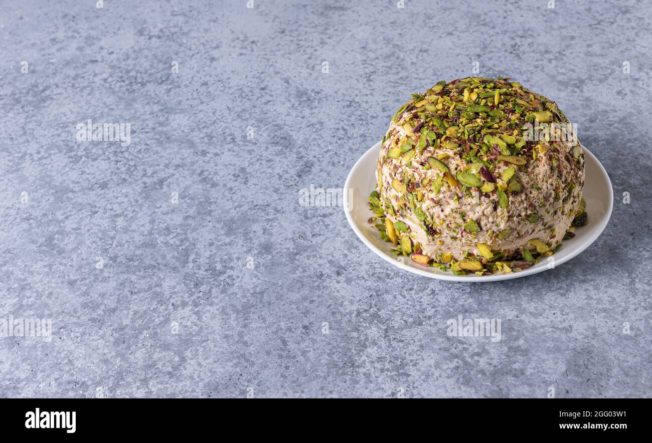 Sesamhalva mit gehackten Pistazien auf weißem Teller auf grauem Steingrund. High-Angle-Ansicht. Speicherplatz kopieren. Traditionelle süsse aus dem Nahen Osten. Jüdisch, Stockfoto