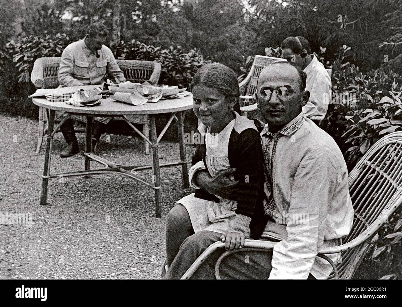 Der NKWD-Chef Lavrenti Beria mit Stains Tochter Svetlana saß auf seinem Schoß. Stalin sitzt an einem Tisch im Hintergrund Stockfoto