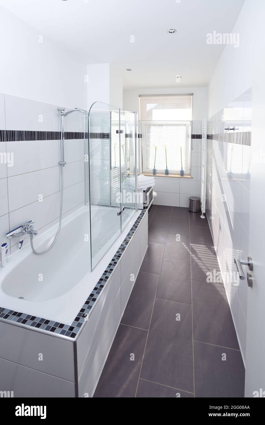 Elegantes, stilvolles Badezimmer Hotel mit weißen Fliesen, grauem Boden,  Wanne, Dusche, hintergrundbeleuchtetes Fenster Stockfotografie - Alamy