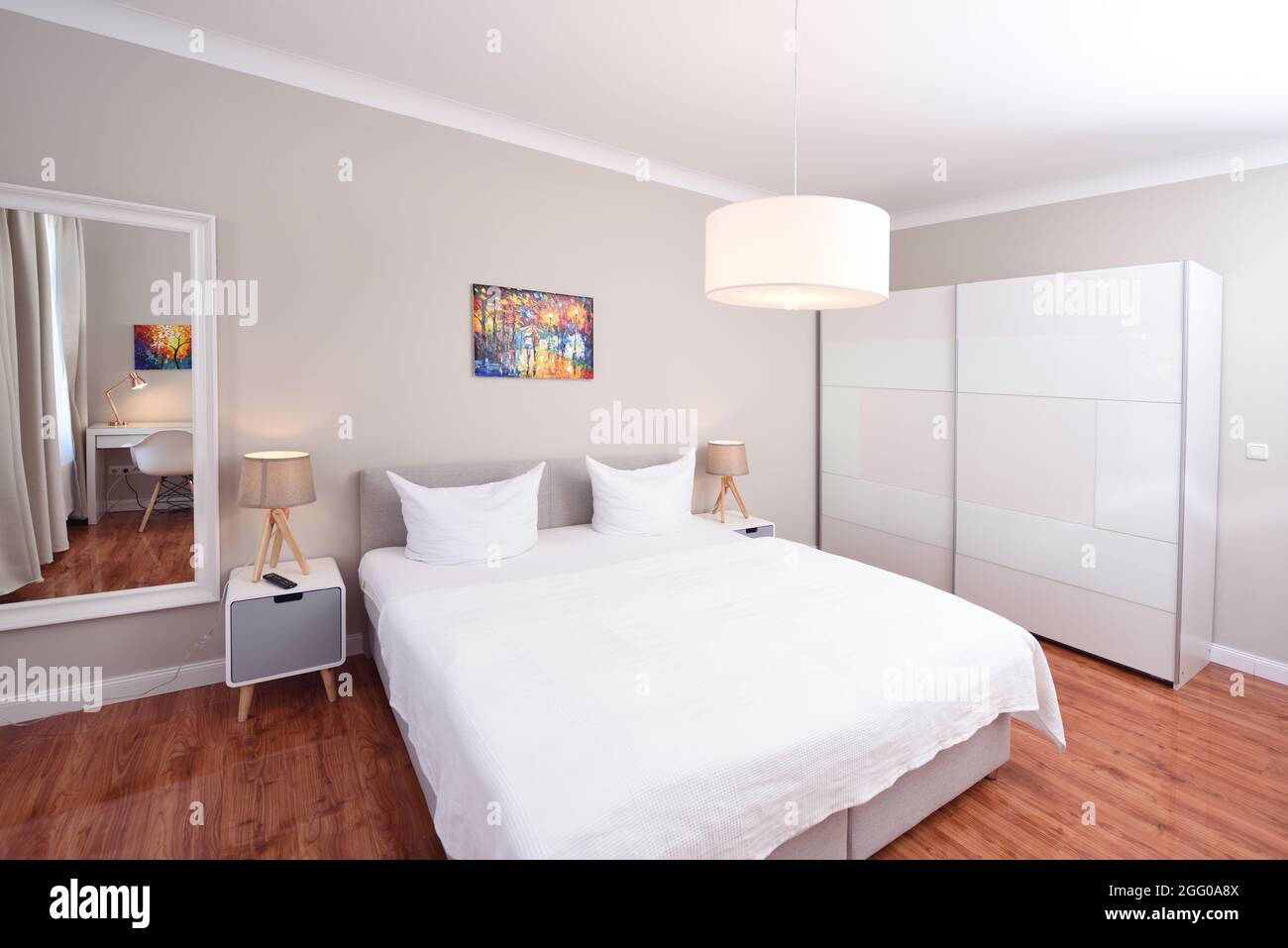 Heim Schlafzimmer Innenraum weißes Bett Holzboden Tür zum Flur bunte Bild Lampen Spiegel Schreibtisch Ecke Stockfoto