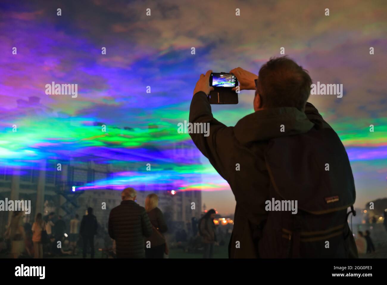Greenwich, London, Großbritannien. August 2021. Die Menschen beobachten das Spektakel. An seiner offiziellen öffentlichen Startnacht beleuchtet „Borealis“ von Dan Archer den Himmel über dem Old Royal Naval College im Royal Borough of Greenwich. „Borealis“ ist eine faszinierende Nachbildung der Nordlichter am Himmel. Es ist Teil des jährlichen Greenwich and Docklands Festivals, das vom 27. August bis 11. September 2021 stattfindet. Kredit: Imageplotter/Alamy Live Nachrichten Stockfoto