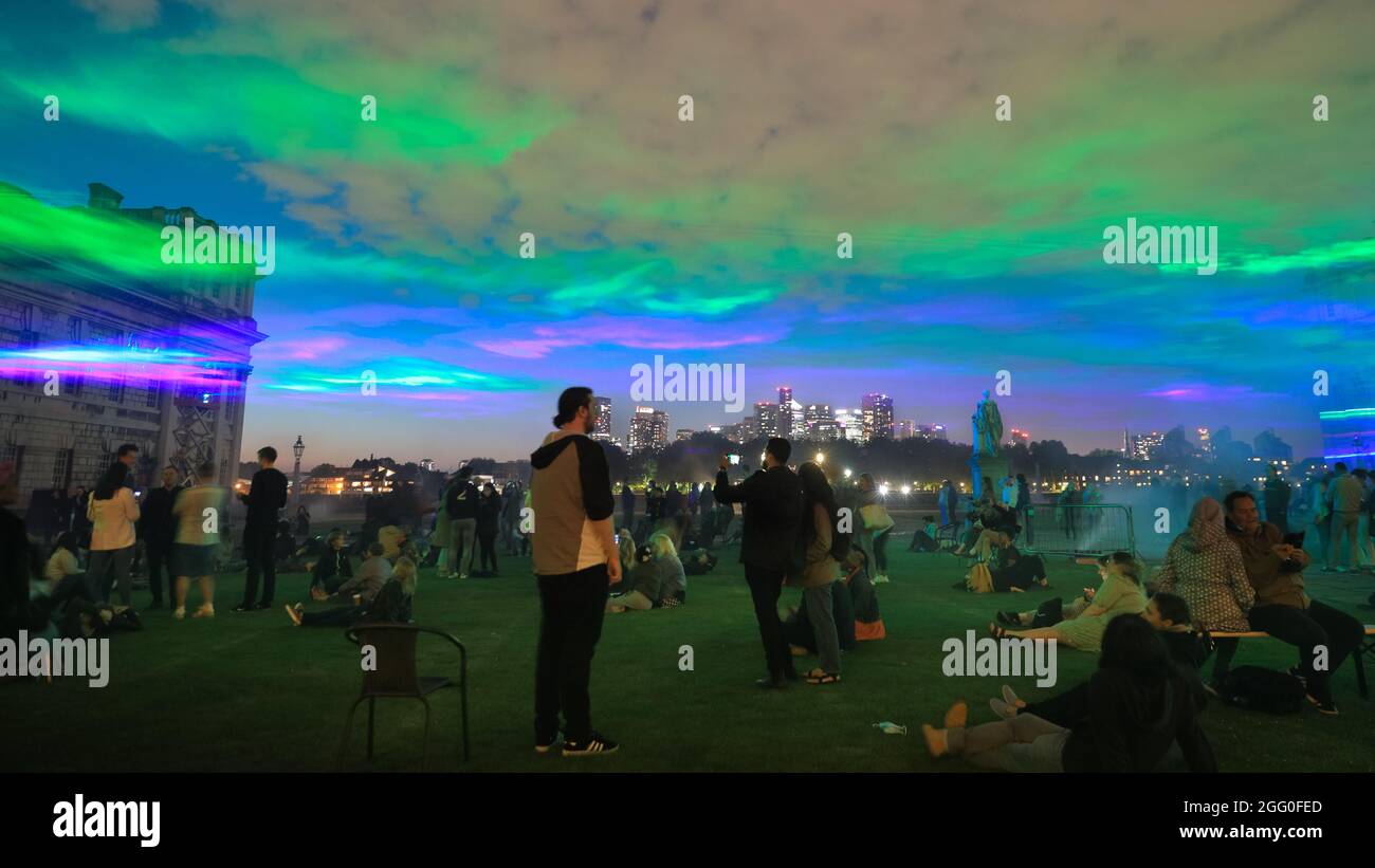 Greenwich, London, Großbritannien. August 2021. Die Menschen beobachten das Spektakel. An seiner offiziellen öffentlichen Startnacht beleuchtet „Borealis“ von Dan Archer den Himmel über dem Old Royal Naval College im Royal Borough of Greenwich. „Borealis“ ist eine faszinierende Nachbildung der Nordlichter am Himmel. Es ist Teil des jährlichen Greenwich and Docklands Festivals, das vom 27. August bis 11. September 2021 stattfindet. Kredit: Imageplotter/Alamy Live Nachrichten Stockfoto