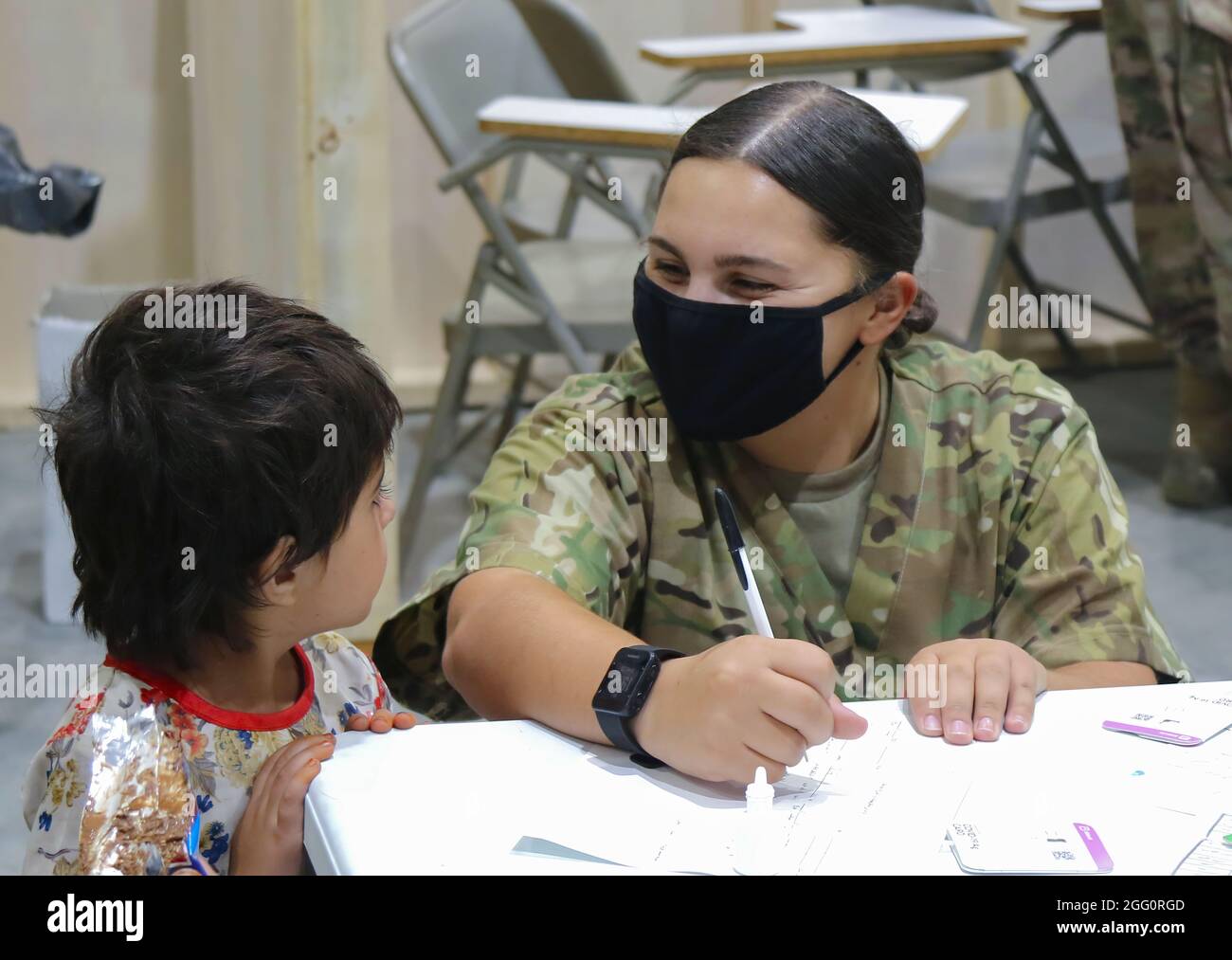 Ein Soldat der US-Armee der Nationalgarde, der der Task Force Spartan, US Army Central, zugewiesen wurde, unterstützt einen afghanischen Evakuierten mit einem medizinischen Screening-Prozess als einen der ersten Schritte bei seiner Ankunft im Lager Buehring, Kuwait, am 25. August 2021. USARCENT-Soldaten aller Komponenten arbeiten weiterhin mit ihren Teamkollegen des US-Zentralkommandos und des Außenministeriums zusammen, um die Evakuierungsbemühungen in Afghanistan mit Transport, Sicherheit, Logistik und medizinischer Hilfe an Standorten in Kuwait zu unterstützen. (USA Armeefoto von PFC. Katelynn Bissell) Stockfoto