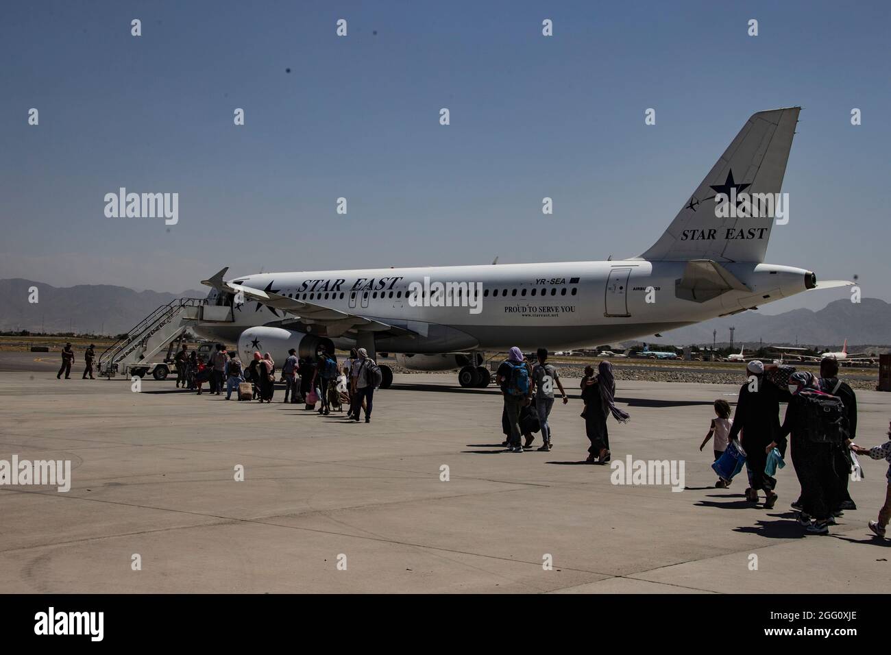 Eine Marine, die der 24. Marine Expeditionary Unit zugewiesen wurde, begleitet Evakuierte zu einem Flugzeug am Hamid Karzai International Airport, Afghanistan, August 25. US-Dienstmitglieder unterstützen das Außenministerium bei einer nicht-kämpferischen Evakuierungsoperation (NEO) in Afghanistan. (USA Marine Corps Foto von CPL. Davis Harris) Stockfoto