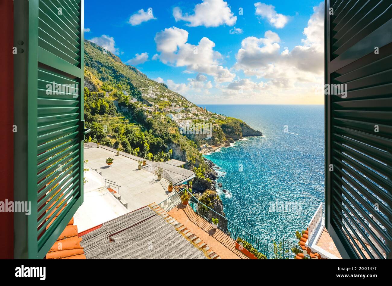 Blick durch ein offenes Fenster mit Fensterläden auf die am Meer gelegene Stadt Praiano, Italien, entlang der Amalfiküste. Stockfoto