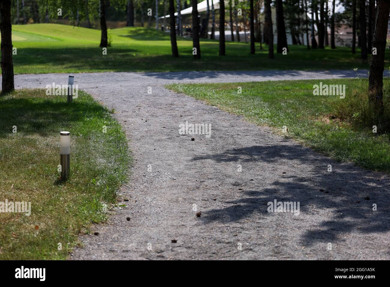 Schotterweg im Park, Laternen an den Seiten Stockfoto