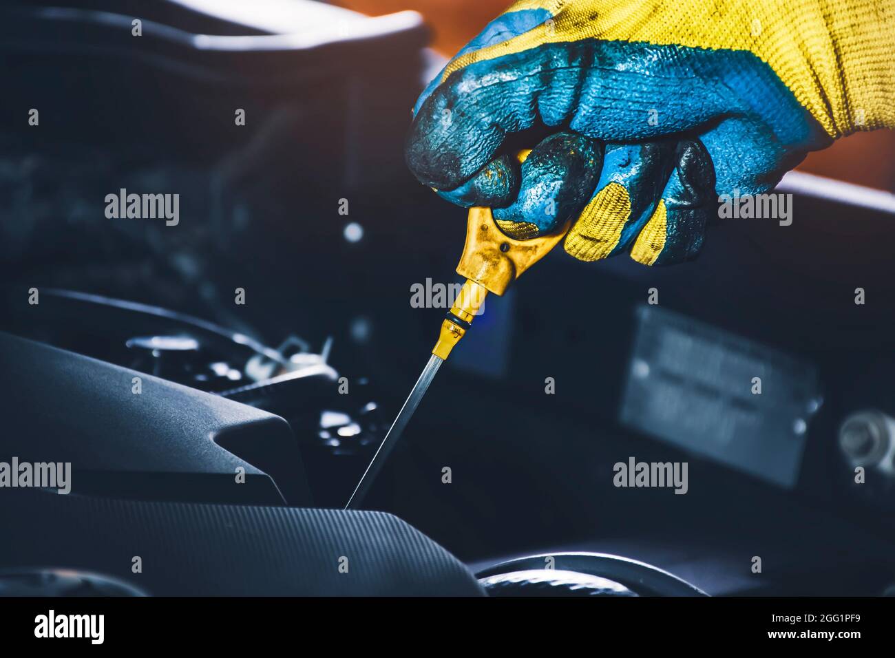 Techniker, der per Hand an einem Ölmessstab zieht, um den Schmierölstand des Automotors zu prüfen Stockfoto