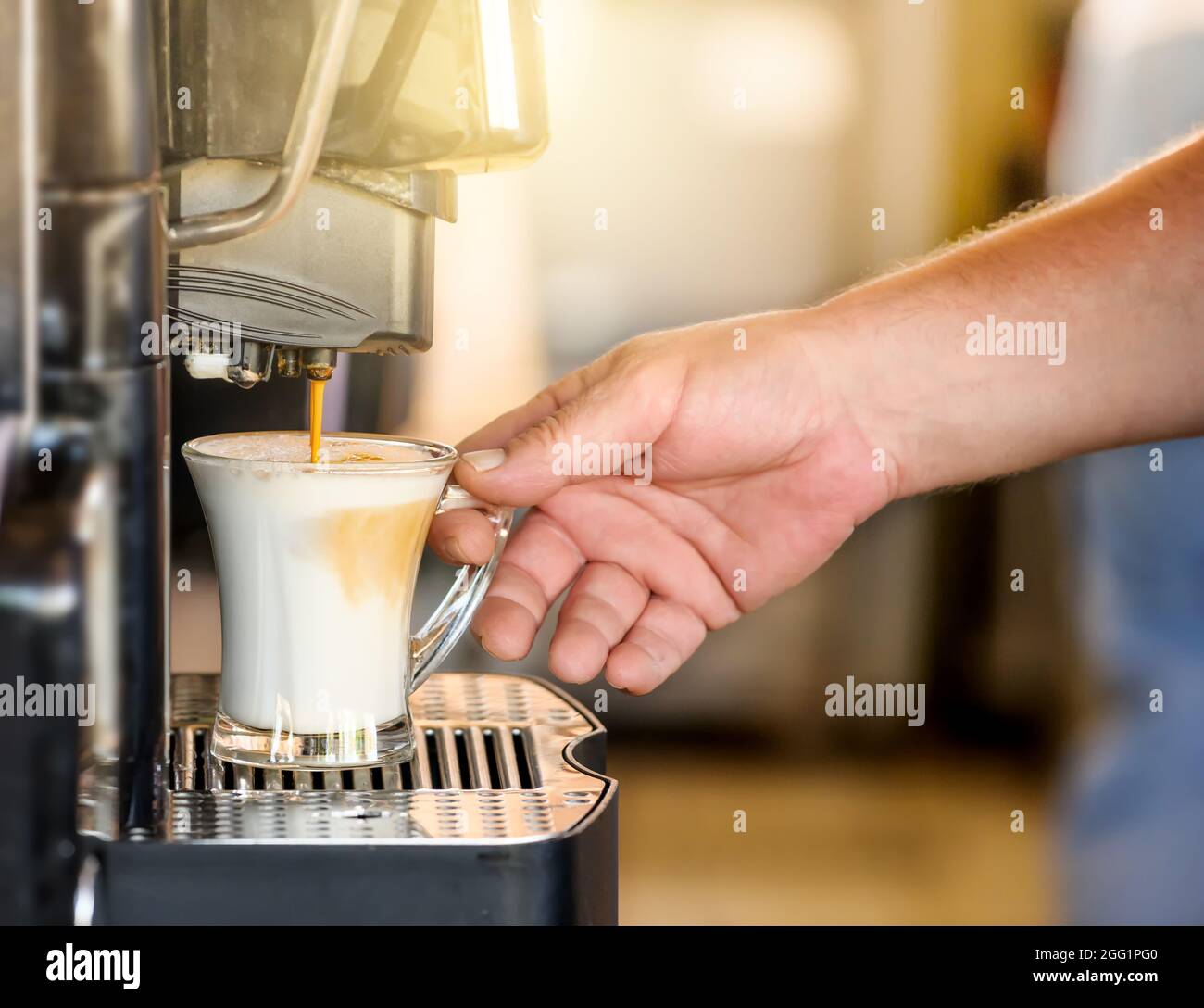 Kaffeetasse mit der Hand in einer automatischen Kaffeemaschine. Stockfoto