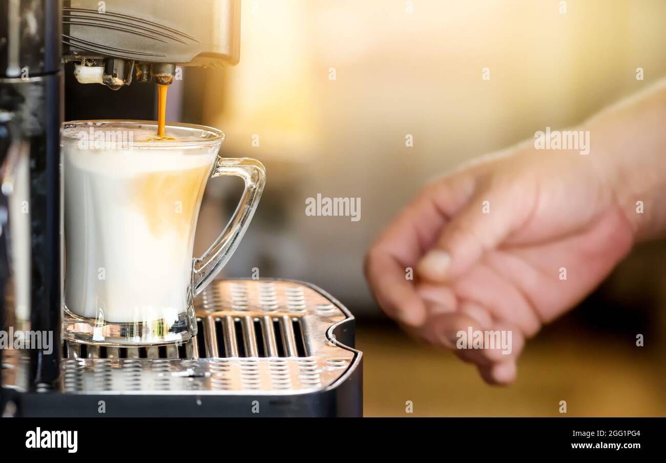 Kaffeetasse mit der Hand in einer automatischen Kaffeemaschine. Stockfoto