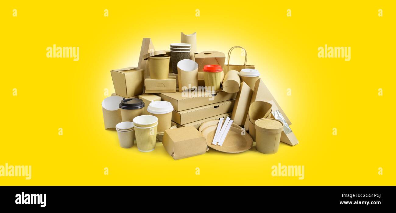 Viele verschiedene Lebensmittelbehälter zum Mitnehmen, Pizzaschachteln, Kaffeetassen im Halter und Pappschachteln auf gelbem Hintergrund. Stockfoto