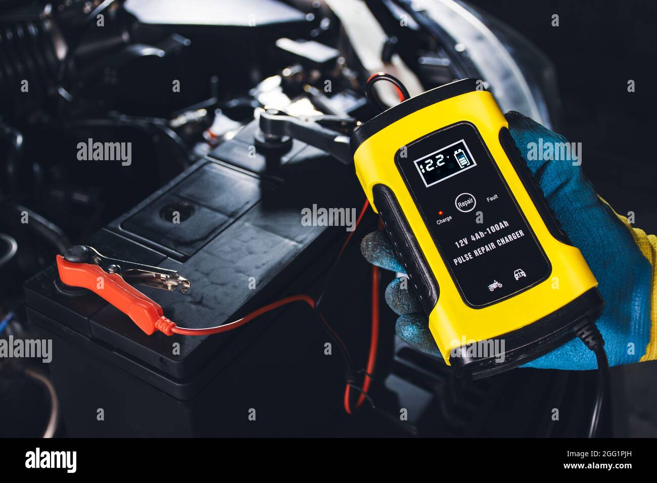 Techniker laden Autobatterie mit automatischem Batterieladegerät in der Reparaturwerkstatt auf Stockfoto