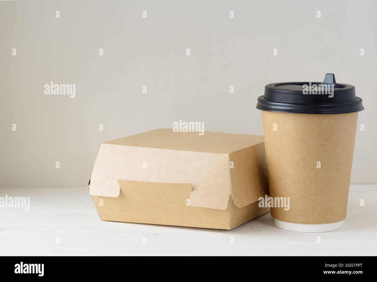 Kaffeetasse aus Papier und Lebensmittelbox auf dem Tisch Stockfoto
