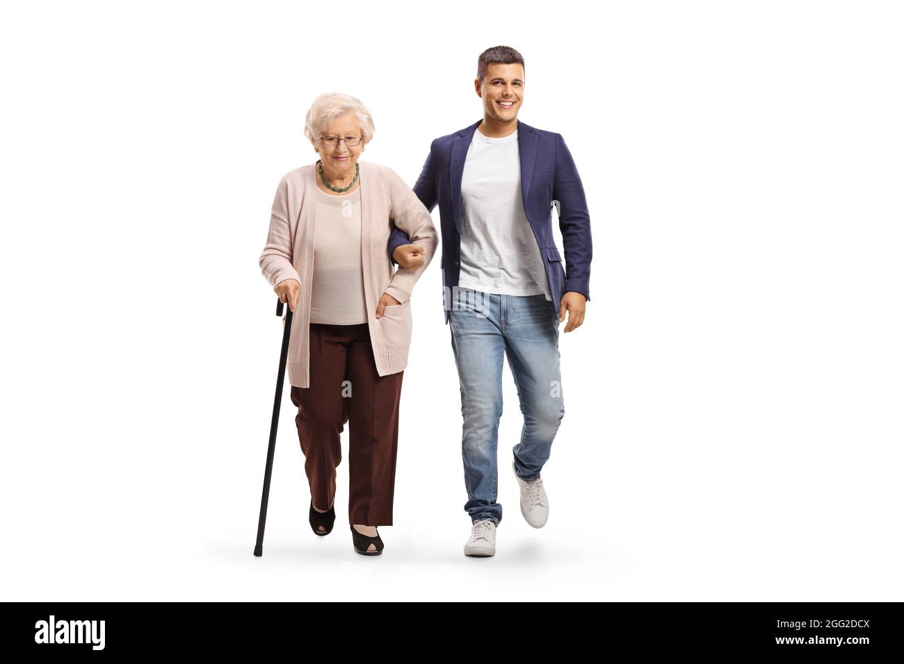 Ganzkörperportrait eines jungen Mannes, der einer älteren Dame mit einem Gehstock hilft, der auf weißem Hintergrund isoliert ist Stockfoto