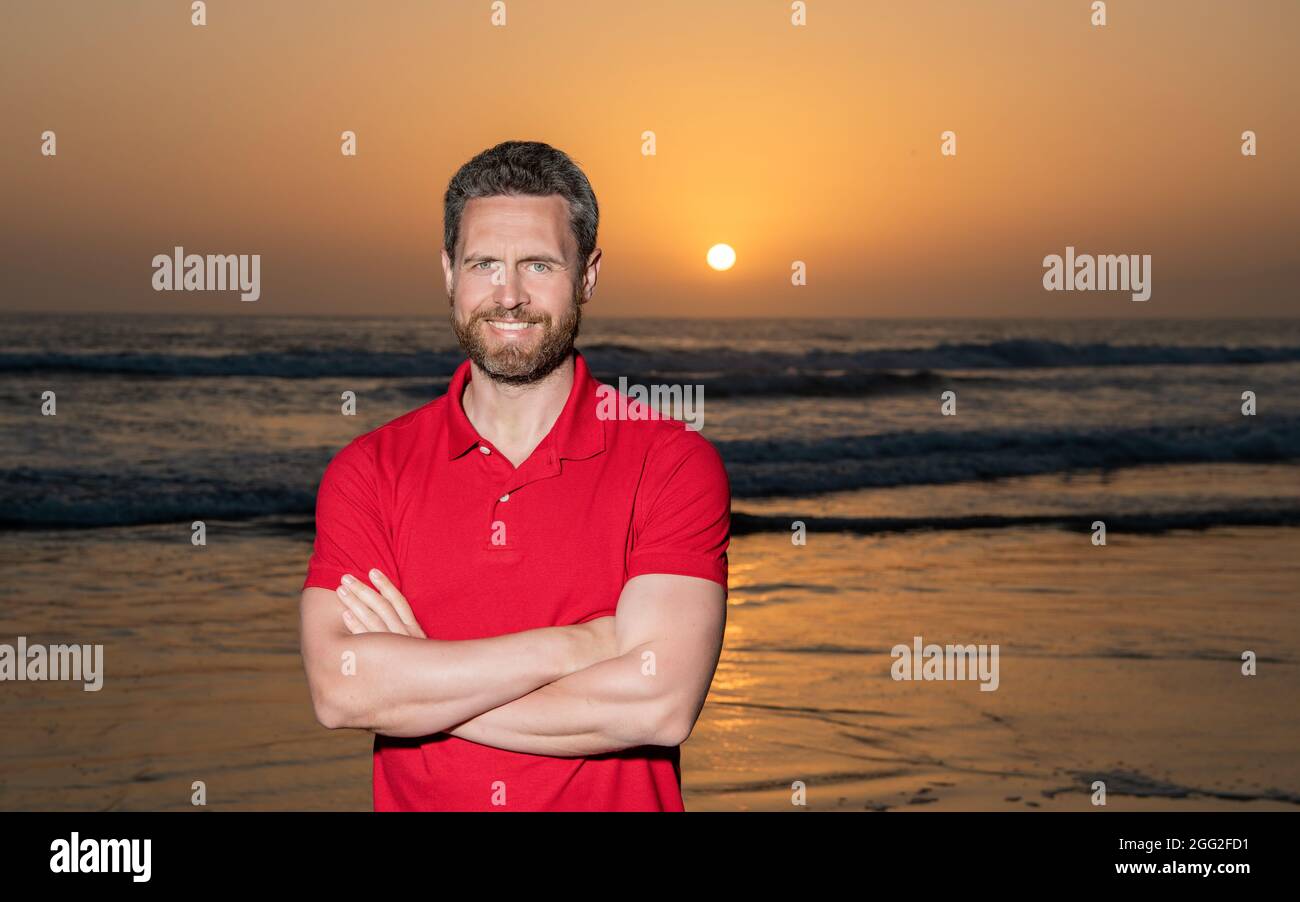 Fröhlicher Mann über dem Meer am Sonnenuntergang Sommerstrand, Platz kopieren, Urlaub Stockfoto