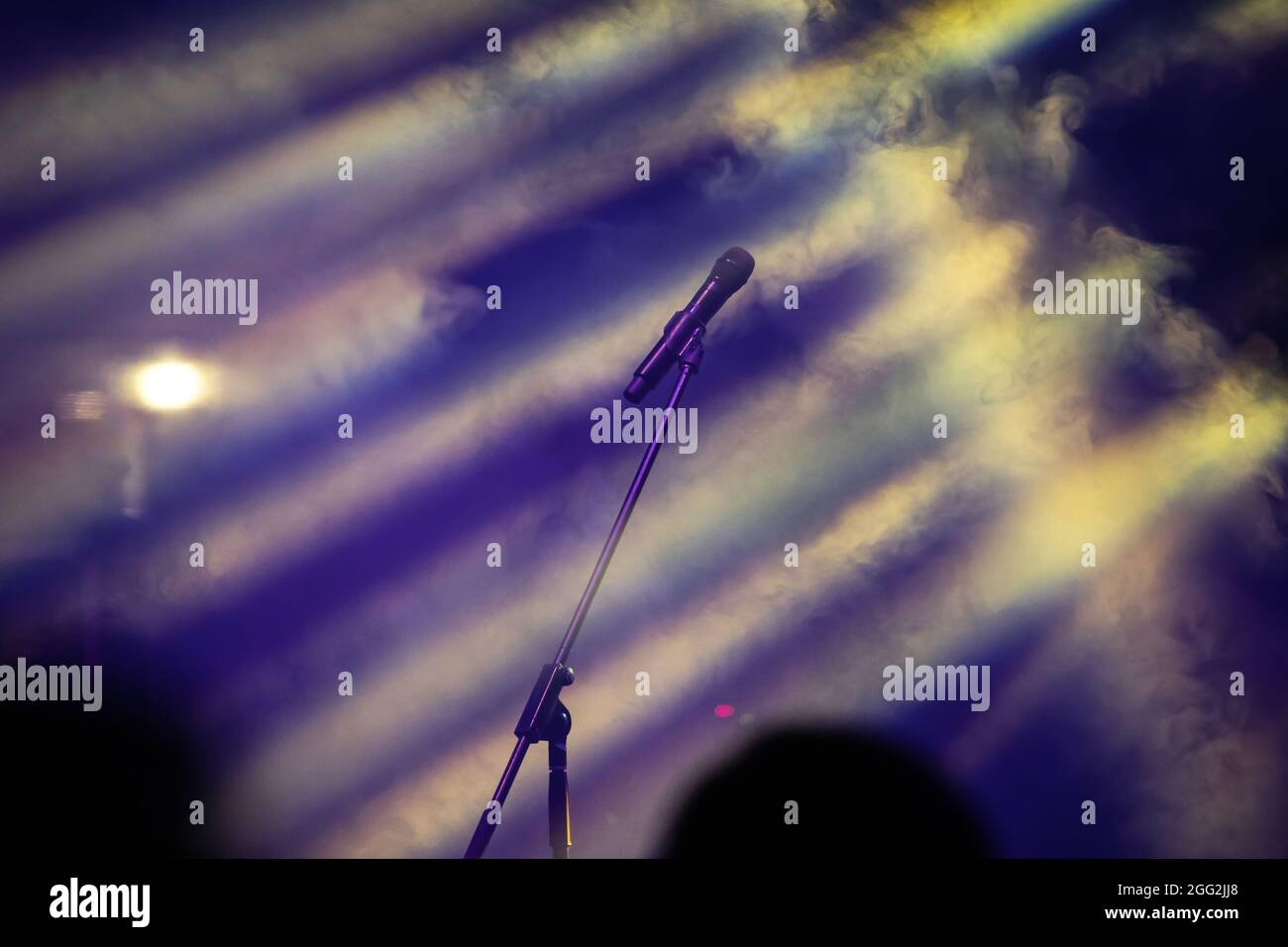 Mikrofon in Bühnenbeleuchtung mit farbigen Scheinwerfern und Rauch. Konzert- und Theaterszene Stockfoto
