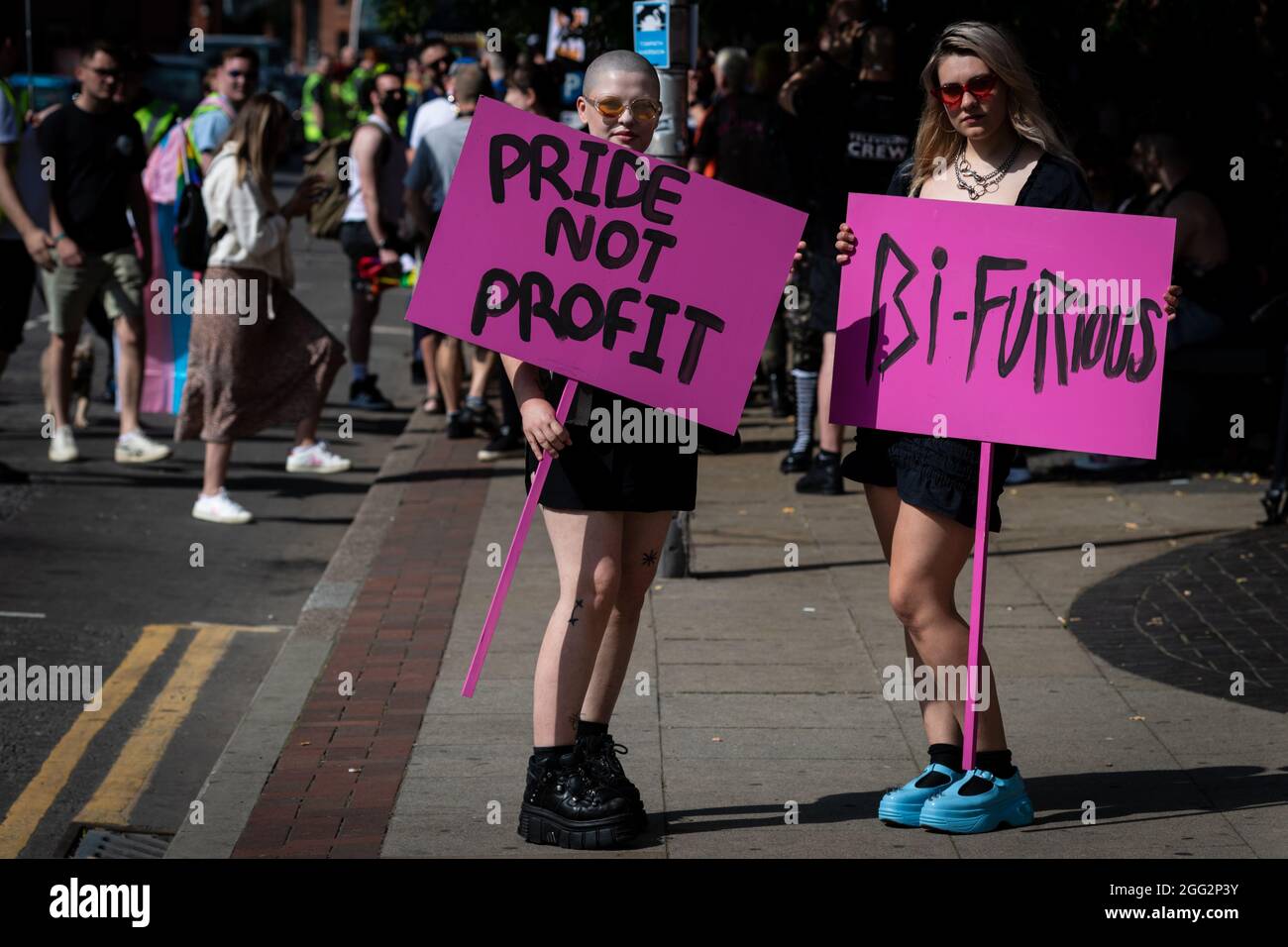 Manchester, Großbritannien. August 2021. Zwei Demonstranten mit Plakaten warten auf den Beginn des Pride-Protests. Hunderte von Menschen marschieren durch die Stadt, um gegen Manchester Pride Ltd zu protestieren.die Demonstranten fordern eine verbesserte Finanzierung für die LGBTQIA-Wohltätigkeitsorganisationen und Gemeindegruppen von Manchester. Kredit: Andy Barton/Alamy Live Nachrichten Stockfoto