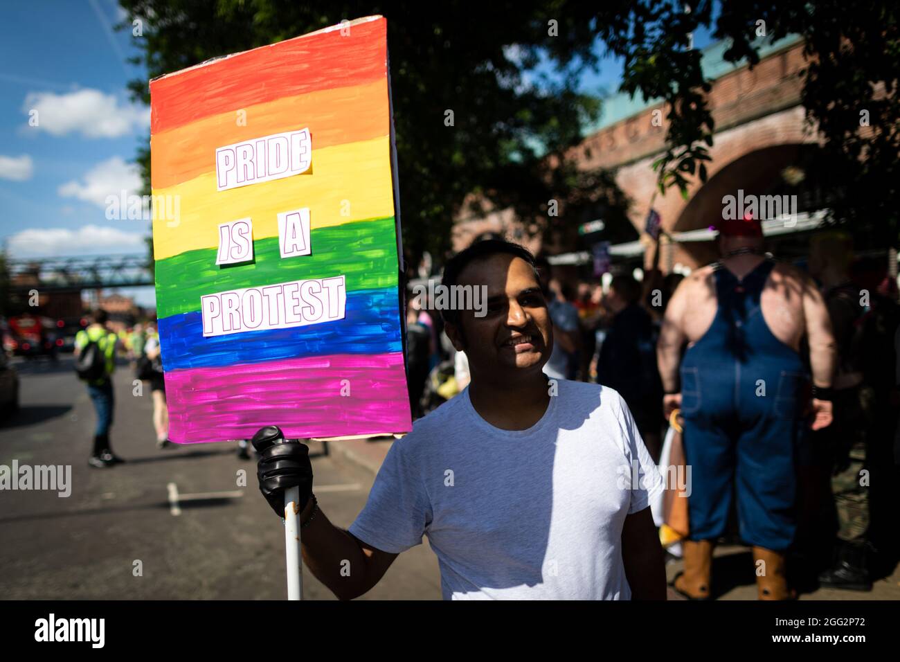 Manchester, Großbritannien. August 2021. Ein Protestler mit Plakat erwartet den Beginn des Pride-Protestes. Hunderte von Menschen marschieren durch die Stadt, um gegen Manchester Pride Ltd zu protestieren.die Demonstranten fordern eine verbesserte Finanzierung für die LGBTQIA-Wohltätigkeitsorganisationen und Gemeindegruppen von Manchester. Kredit: Andy Barton/Alamy Live Nachrichten Stockfoto